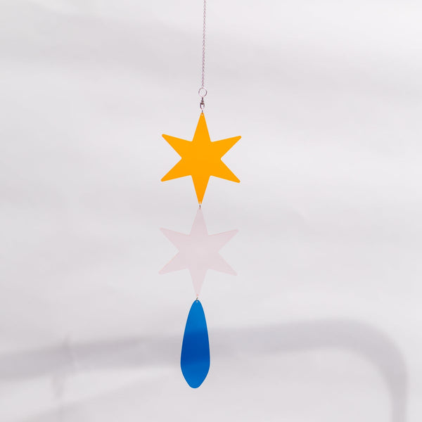 A hanging suncatcher with a yellow five-pointed star, a blue teardrop-shaped tail, and a silver string, shown against a white background with a soft reflection.